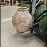 A large brown vase sits on a stand in a store.