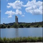 A large building with a clock tower stands over a body of water.