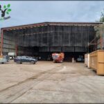 A large building with a metal roof and a car parked outside.