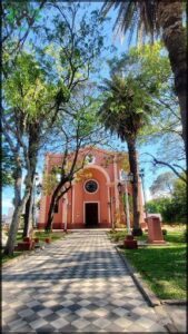A large church with a pink facade stands in the middle of a park.