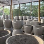 A large collection of clay pots are displayed outside.