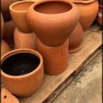 A large collection of clay pots are stacked on a wooden pallet.