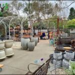 A large collection of pots and vases are displayed in a garden setting.