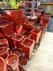 A large collection of red pots and vases are displayed on a table.