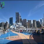 A large cruise ship sails through the city, with a beautiful blue sky above.
