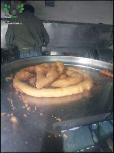 A large, golden-brown pastry is sitting on top of a metal tray, ready to be served.