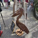 A large metal bird statue is displayed on a sidewalk, attracting the attention of passersby.