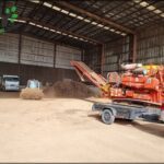 A large orange machine is parked in a dirt lot, possibly for a construction project.