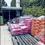 A large pile of bags of dog food is stacked on a wooden pallet.