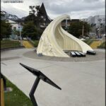 A large white sculpture of a boat is located in a city park.