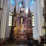 A large wooden church altar with a statue of Mary and a stained glass window.