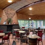 A large wooden dining room with a fireplace and a variety of chairs and tables.