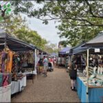 A lively outdoor market with people shopping and vendors selling their wares.