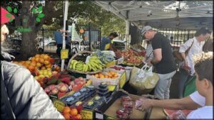 A man and woman are shopping for fruit at a market.
