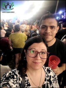 A man and woman pose for a picture at a crowded event.