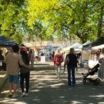 A man and woman walk down a street, enjoying the outdoors and each other's company.