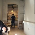 A man in a black shirt is walking down a hallway in a restaurant.