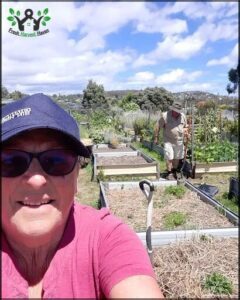 A man is digging in a garden, while a woman takes a picture of him.