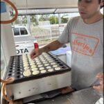 A man is making cookies in a kitchen, placing them on a tray.
