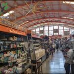 A man is standing in a store, looking at his cell phone.