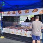 A man is standing in front of a food stand, looking at the menu.