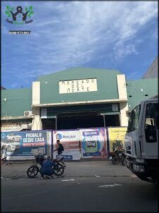 A man on a motorcycle is stopped in front of a building with a sign that says "Mercado Mortte."