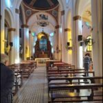 A man stands in front of a church, looking at the pews.