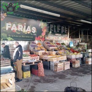 A man stands in front of a fruit stand, surrounded by a variety of fruits and vegetables.