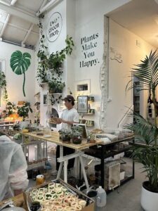 A man stands in front of a table filled with various plants and jars.