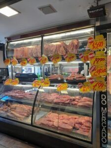 A meat market display with a variety of cuts of meat, including pork and beef, with prices labeled on them.