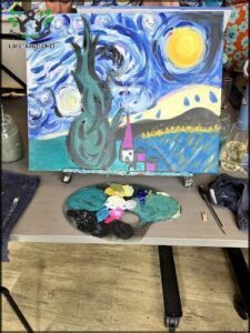 A painting of a tree and a house is displayed on a table.