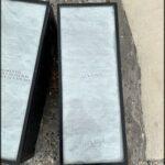 A pair of black and white plaques are laying on the ground, one of which has a signature on it.