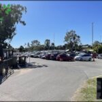 A parking lot filled with cars and trucks, with a blue sky overhead.