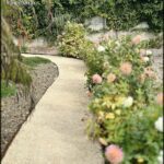 A pathway is lined with flowers and bushes, creating a beautiful and serene atmosphere.