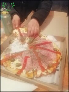 A person is cutting a pizza with pepperoni and olives.