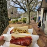 A person is holding a box with two hot dogs in it.