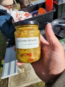 A person is holding a jar of zucchini pickles.