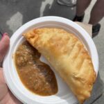 A person is holding a plate with a pastry and a dipping sauce.