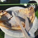A person is holding a plate with a piece of food on it.