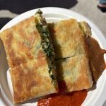 A person is holding a plate with a sandwich on it.