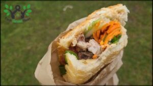 A person is holding a sandwich with carrots and meat in it.