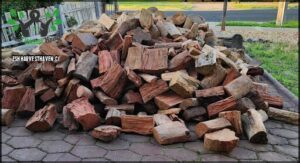 A pile of logs sits on a brick patio.