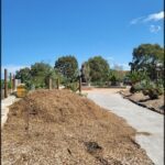 A pile of wood chips sits in a dirt lot, ready for use.