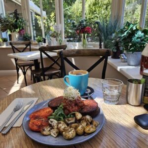 A plate of food sits on a table with a blue cup of coffee.