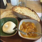 A plate of food with a spoon in a bowl of jam.