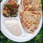 A plate of food with a white sauce and a side of vegetables.
