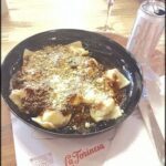 A plate of pasta with a glass of wine on the side.