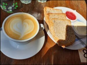 A plate of toast and a cup of coffee on a wooden table.