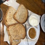 A plate of toast and jam sits on a wooden table.