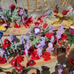 A purple crocheted flower is placed on a grave marker.